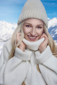 Primo piano di ragazza che indossa un ampio maglione invernale bianco con collo alto e cappello in lana coordinato.