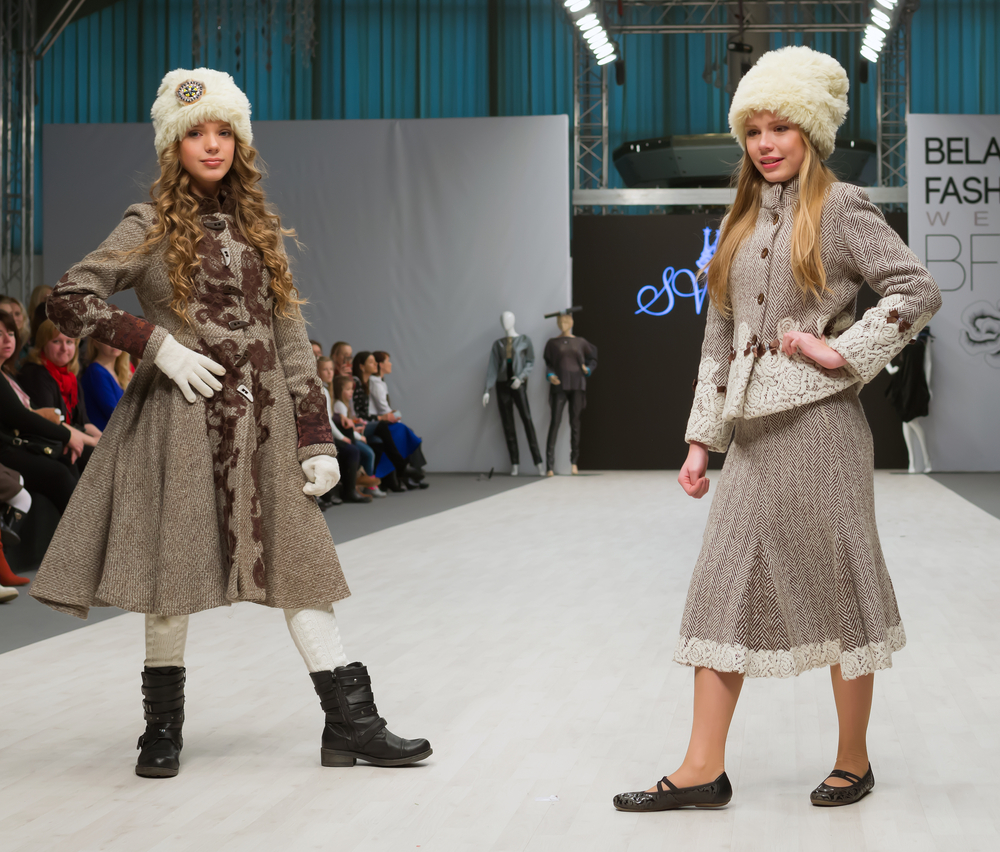 Due bambine ad una sfilata di moda che indossano abiti eleganti invernali con colbacchi di ecopelliccia