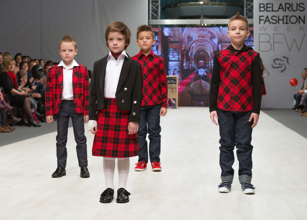 Gruppo di bimbi ad una sfilata che indossano abiti a scacchi stile scozzese