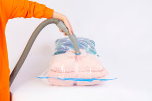 Utilizzo dei sacchi sottovuoto per abiti. Persona che sta utilizzando l'aspiratore per togliere l'aria.