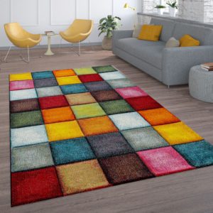 Particolare di salotto con grande tappeto rettangolare a quadrati di diversi colori