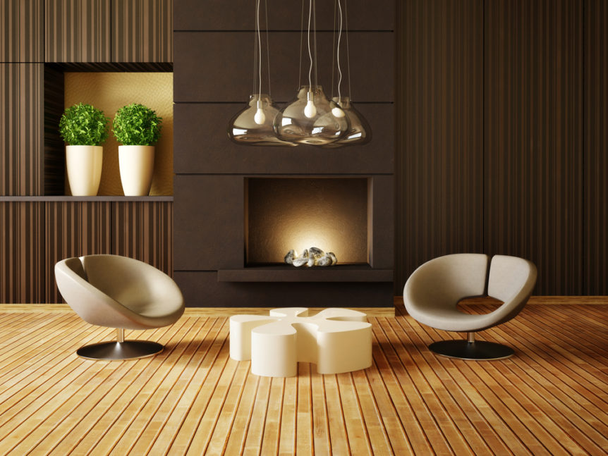 Salotto di design con poltrone, caminetto, lampadario in metallo e vasi con piante verdi. Pavimento in legno naturale